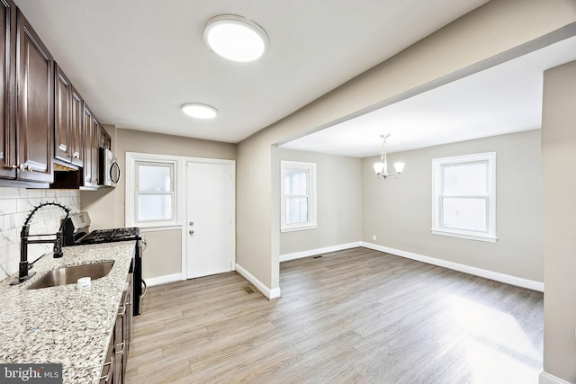 kitchen with sink, dark brown cabinetry, backsplash, stainless steel appliances, and light stone counters