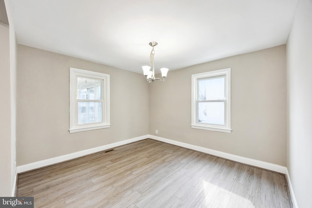 unfurnished room featuring a chandelier, light hardwood / wood-style flooring, and a wealth of natural light