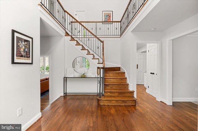 staircase with hardwood / wood-style flooring and a towering ceiling