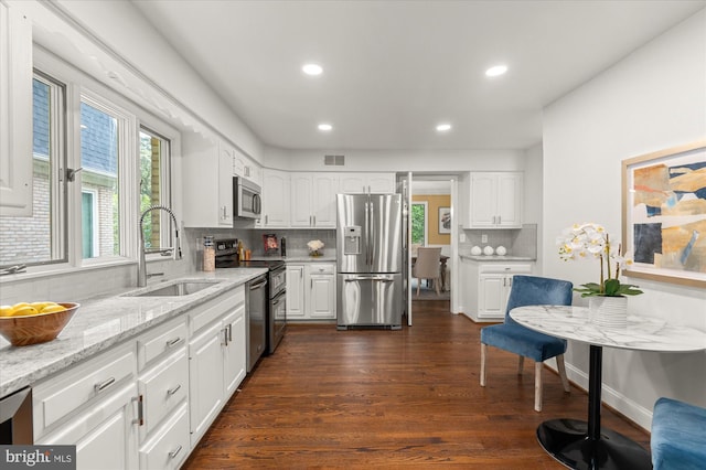 kitchen with sink, tasteful backsplash, white cabinetry, and appliances with stainless steel finishes