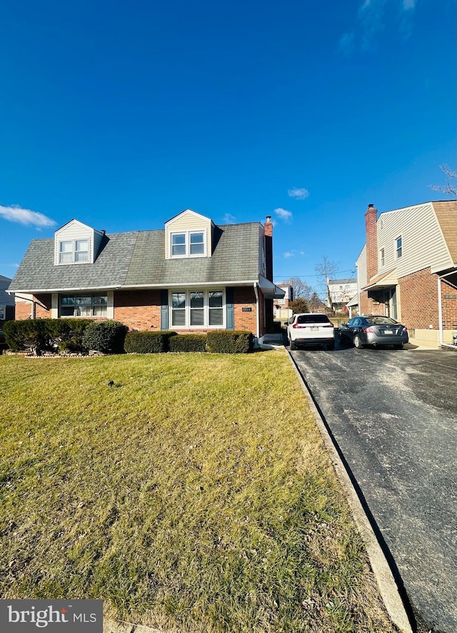 cape cod home featuring a front lawn