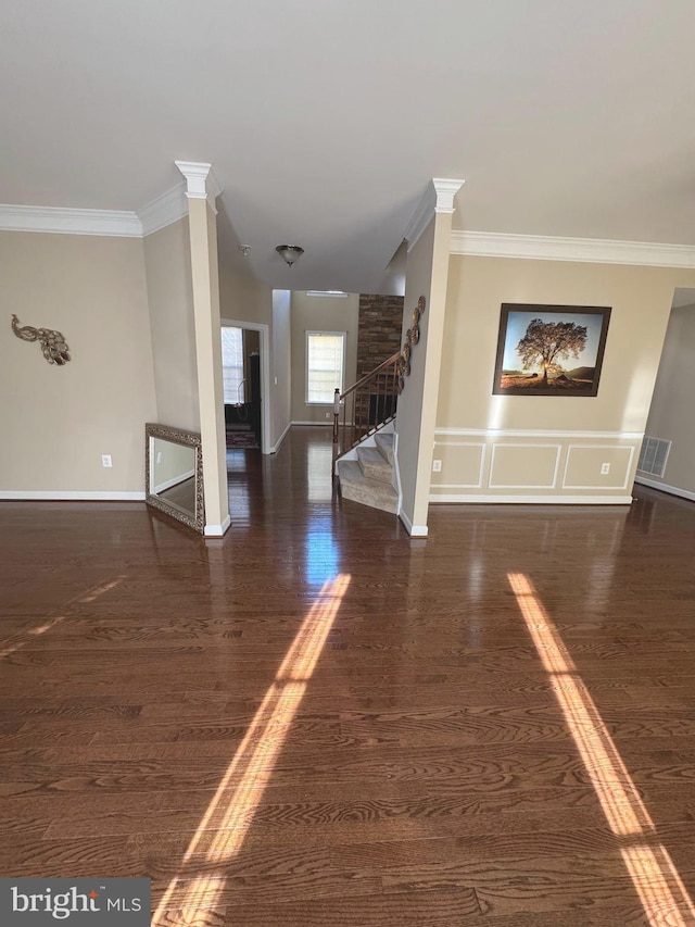 unfurnished living room with stairs, crown molding, wood finished floors, and visible vents