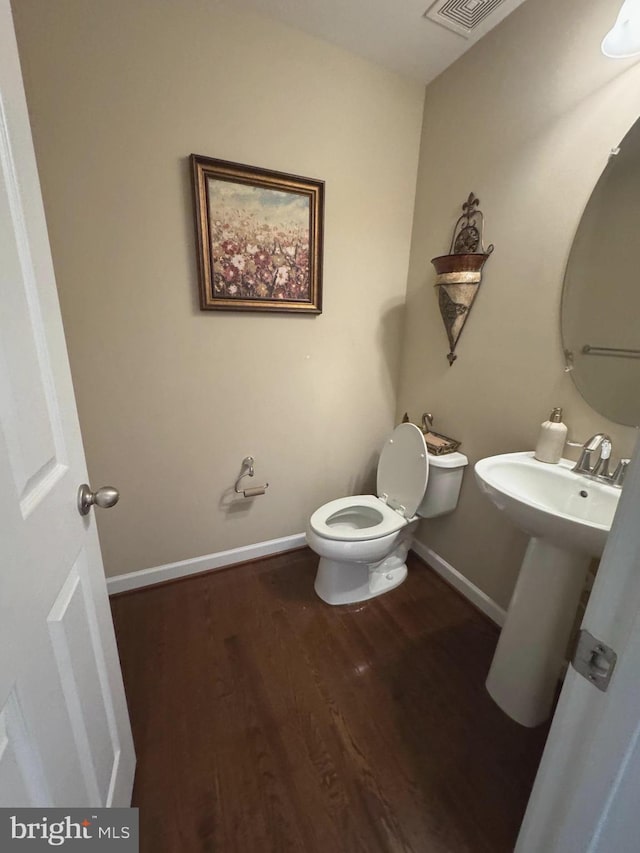 bathroom with visible vents, baseboards, toilet, wood finished floors, and a sink