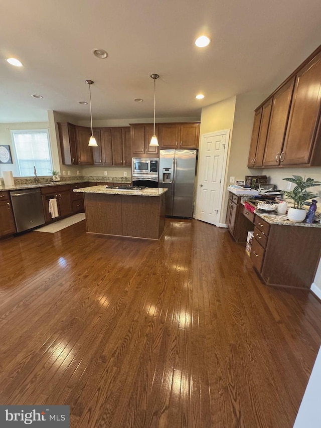 kitchen with dark wood-type flooring, light stone counters, a center island, recessed lighting, and stainless steel appliances