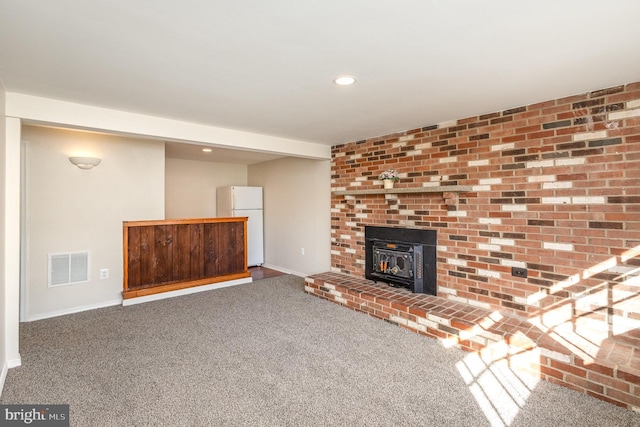 unfurnished living room with a wood stove and carpet