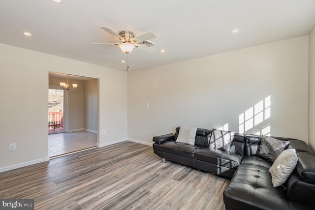 living room featuring ceiling fan with notable chandelier and hardwood / wood-style floors