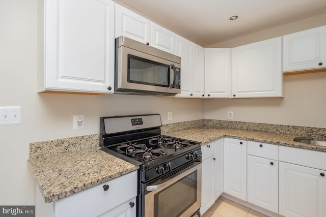 kitchen featuring white cabinets, stainless steel appliances, and light stone counters