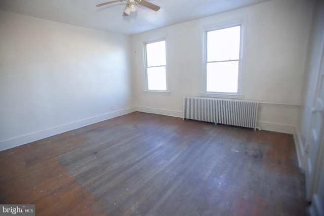 empty room with dark wood-type flooring, radiator heating unit, and ceiling fan