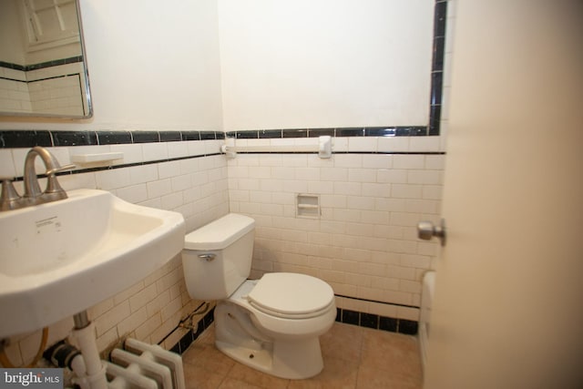 bathroom featuring tile patterned floors, toilet, sink, and tile walls