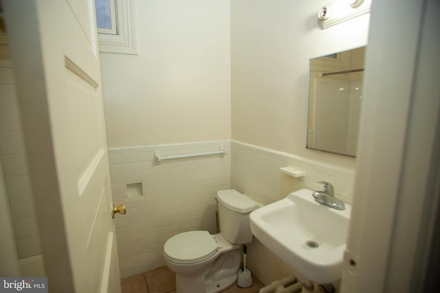 bathroom with tile patterned floors, toilet, sink, and tile walls