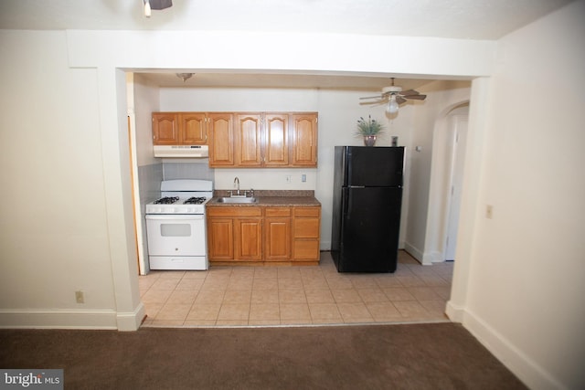 kitchen with sink, black refrigerator, ceiling fan, white range with gas cooktop, and light colored carpet