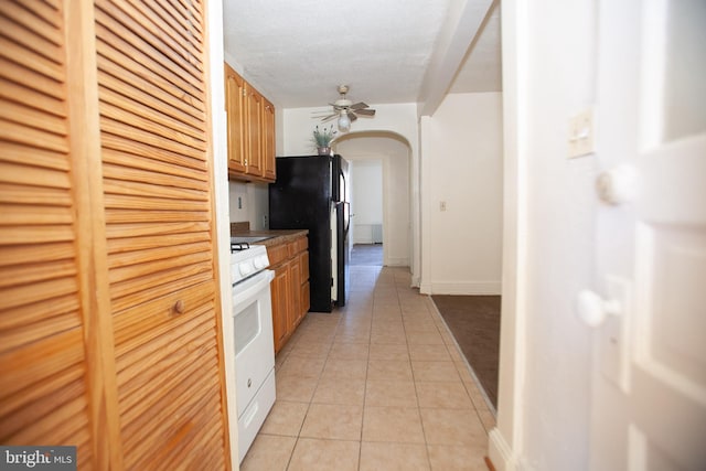 kitchen featuring black refrigerator, white gas range, ceiling fan, and light tile patterned flooring