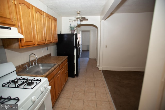 kitchen with sink, black fridge, a textured ceiling, white gas range, and ceiling fan