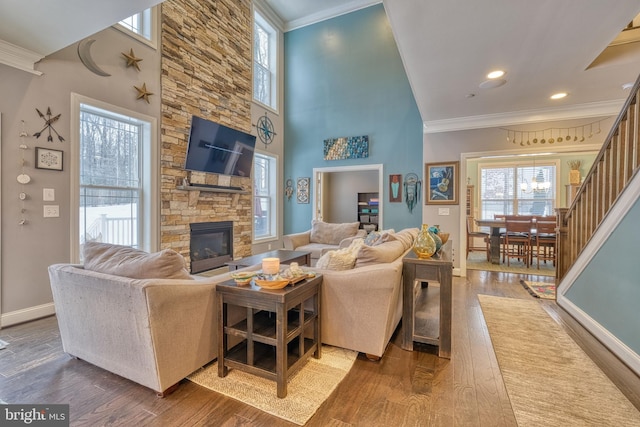 living room with ornamental molding, a towering ceiling, hardwood / wood-style floors, and a fireplace