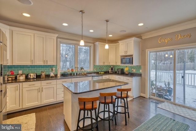 kitchen with built in microwave, white cabinetry, pendant lighting, and a center island