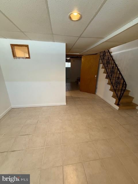 basement with light tile patterned floors and a paneled ceiling