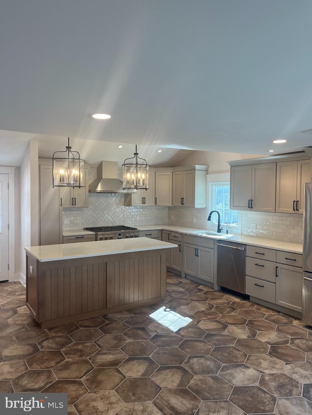 kitchen featuring a center island, gray cabinetry, appliances with stainless steel finishes, a sink, and wall chimney range hood