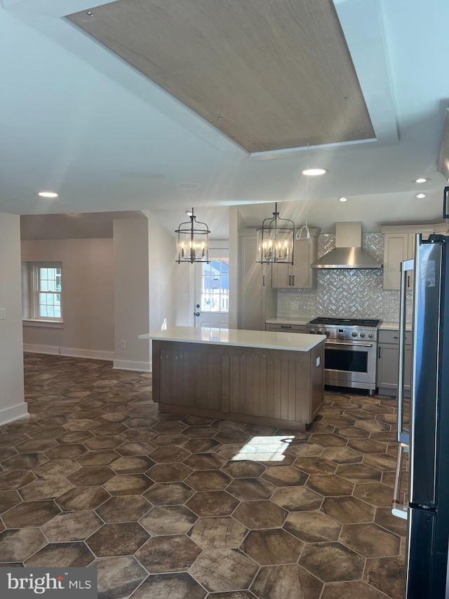 kitchen featuring a kitchen island, stainless steel appliances, light countertops, wall chimney range hood, and backsplash