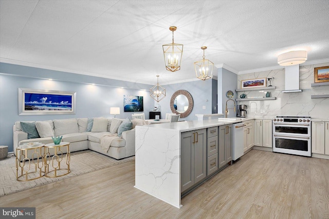 kitchen featuring decorative light fixtures, double oven range, white dishwasher, kitchen peninsula, and light hardwood / wood-style floors