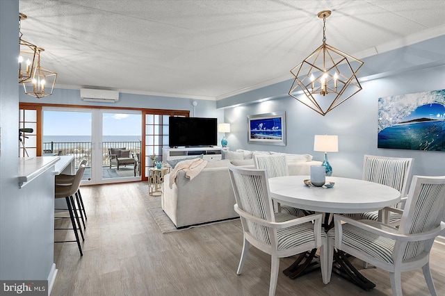 dining area featuring a notable chandelier, light hardwood / wood-style flooring, ornamental molding, and an AC wall unit