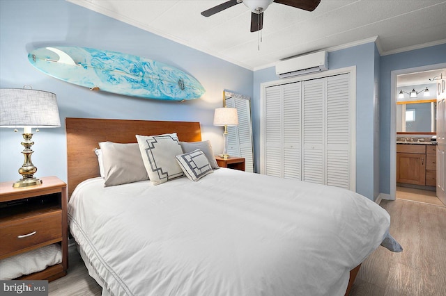 bedroom featuring an AC wall unit, connected bathroom, ornamental molding, light hardwood / wood-style floors, and a closet