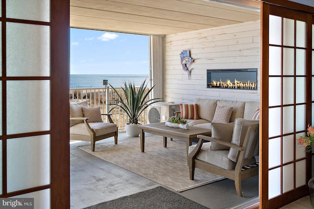 living room featuring a water view and wooden walls