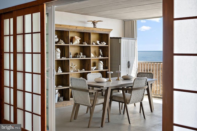 dining area with concrete flooring, expansive windows, and a water view