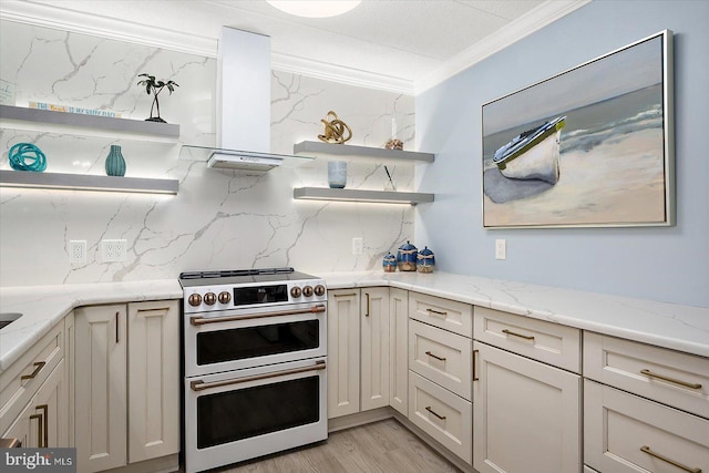 kitchen featuring crown molding, wall chimney range hood, light stone countertops, range with two ovens, and backsplash