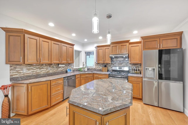 kitchen featuring pendant lighting, appliances with stainless steel finishes, a kitchen island, sink, and stone countertops