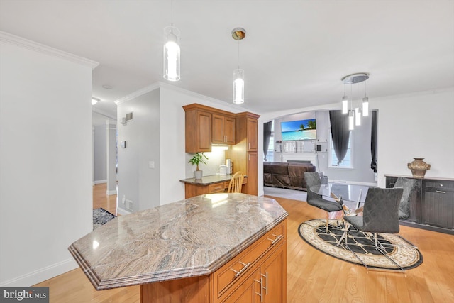 kitchen featuring light hardwood / wood-style floors, decorative light fixtures, ornamental molding, and a kitchen island