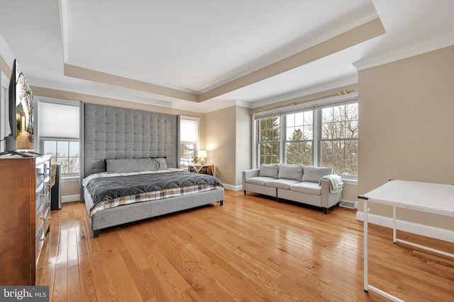 bedroom featuring light hardwood / wood-style floors, a tray ceiling, and ornamental molding