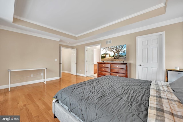 bedroom with hardwood / wood-style flooring, a tray ceiling, and ornamental molding