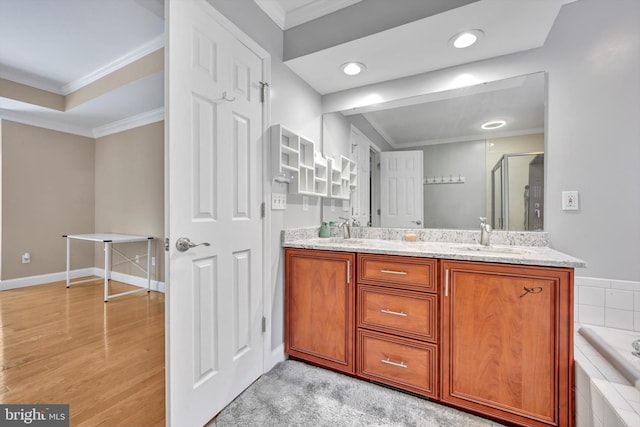 bathroom with wood-type flooring, vanity, crown molding, and independent shower and bath