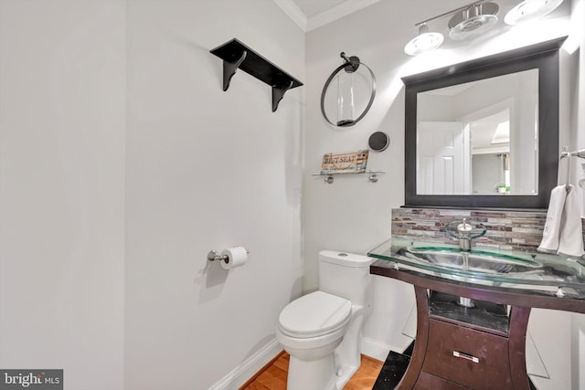 bathroom with toilet, hardwood / wood-style floors, tasteful backsplash, ornamental molding, and vanity