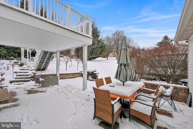 snow covered patio featuring a balcony and a grill