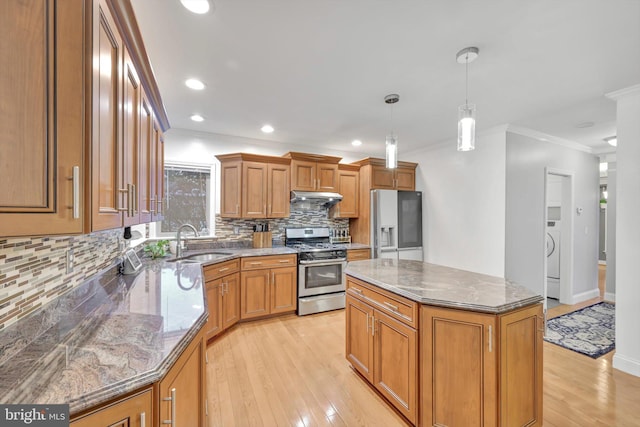 kitchen featuring pendant lighting, a kitchen island, stainless steel appliances, sink, and light stone counters