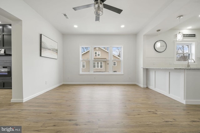 unfurnished living room with ceiling fan and light hardwood / wood-style flooring