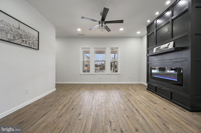 unfurnished living room with ceiling fan and wood-type flooring