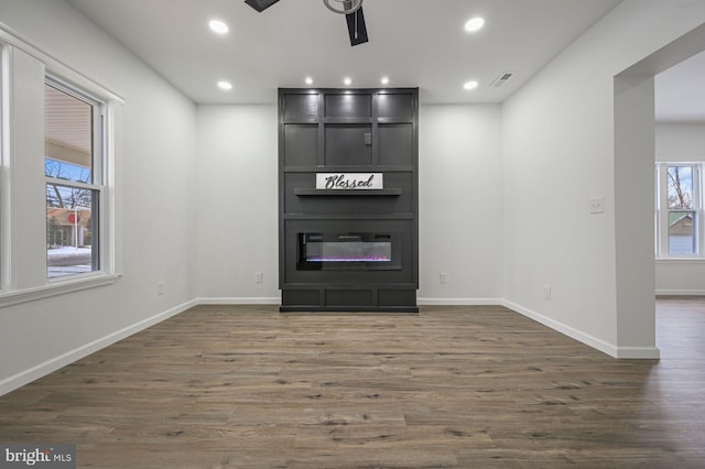 unfurnished living room with a large fireplace, ceiling fan, and dark hardwood / wood-style floors