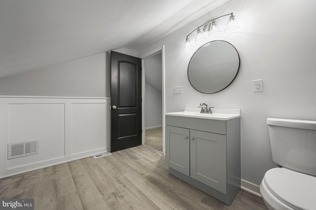 bathroom featuring hardwood / wood-style flooring, toilet, vanity, and vaulted ceiling