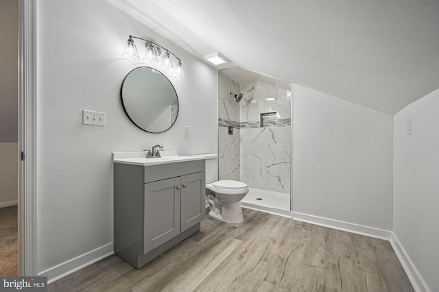 bathroom with hardwood / wood-style floors, tiled shower, vanity, and toilet