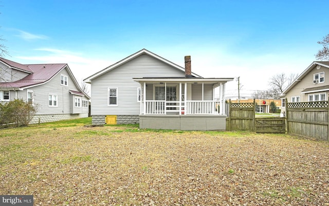 rear view of property featuring a yard and a porch