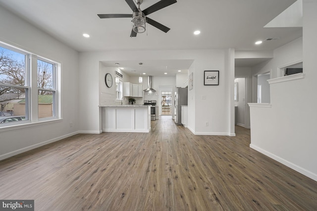 unfurnished living room with ceiling fan, plenty of natural light, hardwood / wood-style floors, and sink