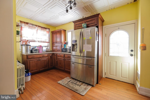 kitchen featuring radiator heating unit, light wood-type flooring, and stainless steel fridge with ice dispenser