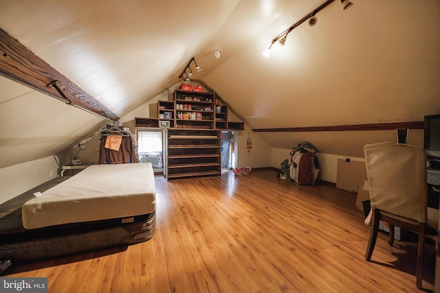 bedroom featuring rail lighting, vaulted ceiling, and light hardwood / wood-style flooring