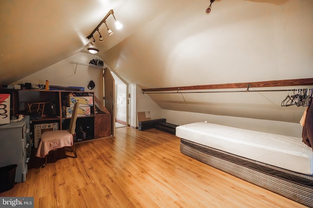 bedroom with lofted ceiling, hardwood / wood-style floors, and rail lighting