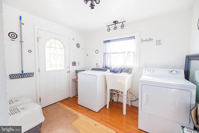 washroom featuring sink, light hardwood / wood-style floors, and washing machine and clothes dryer