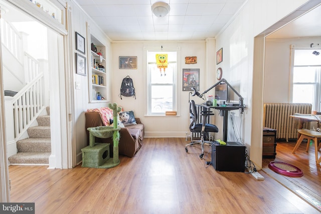 misc room featuring hardwood / wood-style flooring, radiator heating unit, built in shelves, and a wealth of natural light