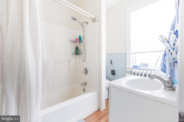 full bathroom with sink, shower / tub combo, hardwood / wood-style floors, tile walls, and toilet