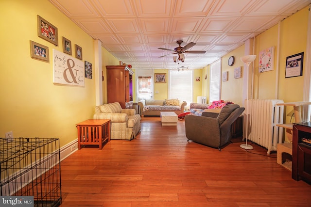 living room featuring hardwood / wood-style flooring, ceiling fan, and radiator heating unit